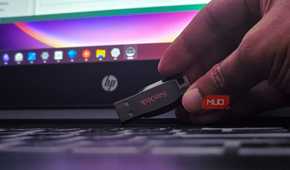 Human hand holding a sandisk USB drive on a laptop keyboard