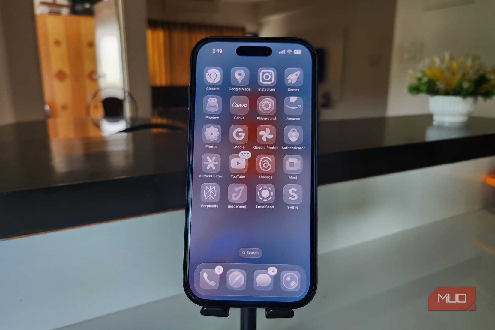 iPhone 16 Pro showing iOS 26 home screen on a stand