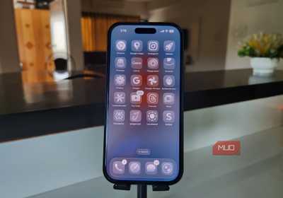 iPhone 16 Pro showing iOS 26 home screen on a stand