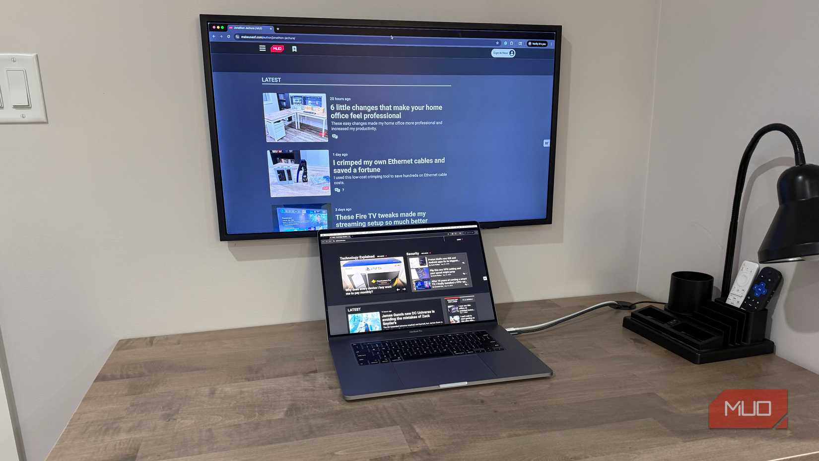 MacBook Pro on desk with wall mounted samsung frame and desk grommet for cables