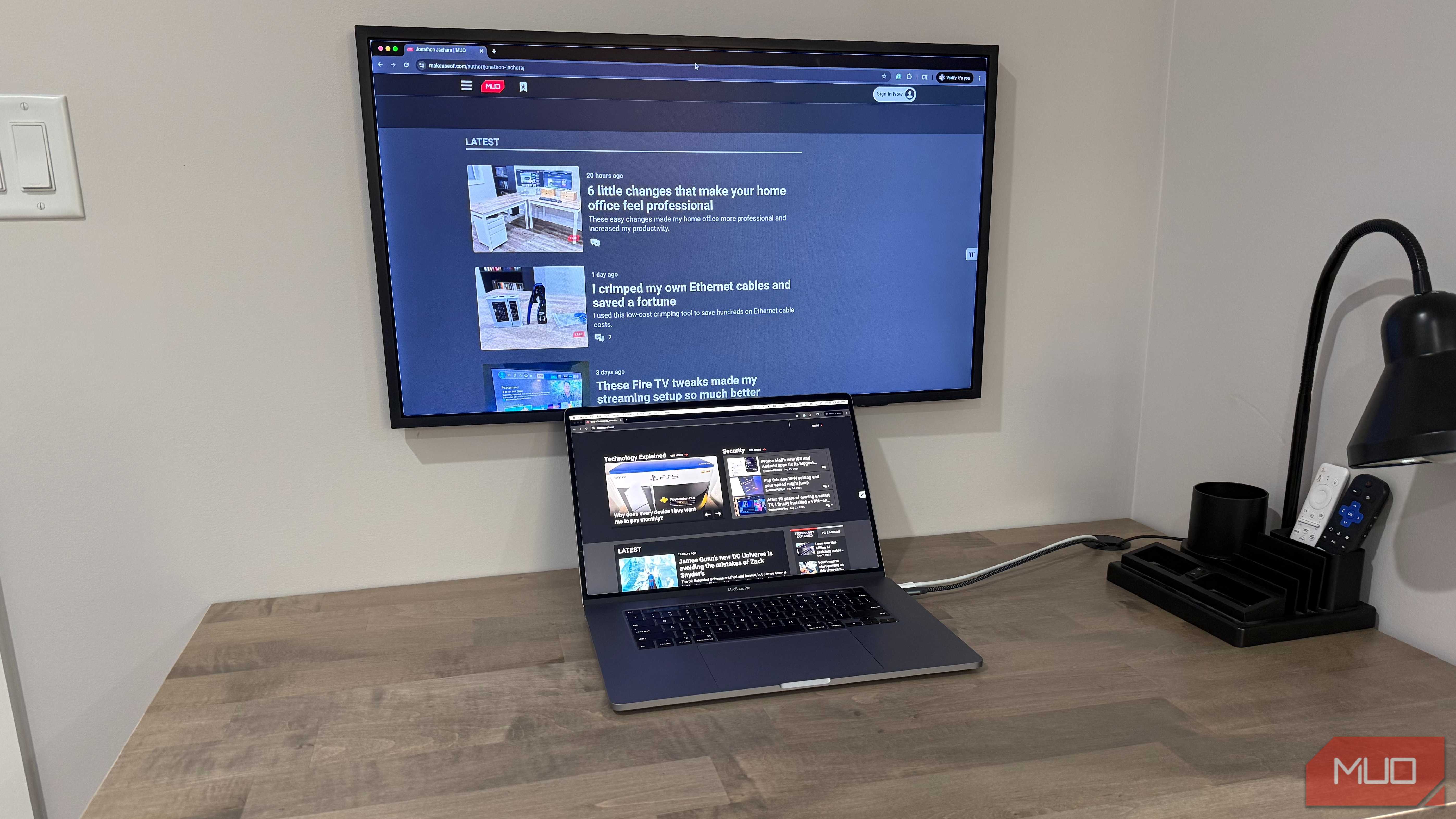 MacBook Pro on desk with wall mounted samsung frame and desk grommet for cables