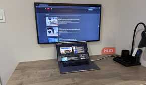 MacBook Pro on desk with wall mounted samsung frame and desk grommet for cables