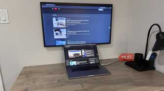 MacBook Pro on desk with wall mounted samsung frame and desk grommet for cables