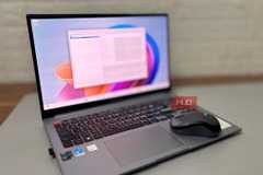 Open laptop with a blurred screen running X-Mouse Button Control and a Logitech wireless mouse placed beside it on a desk.-1