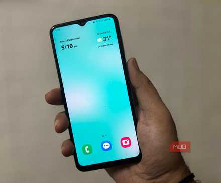 شخصی که تلفن سامسونگ را در دست دارد و صفحهخانهی تمیز با ساعت و وضعیت هوا را نشان میدهد