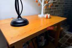 A wooden table sitting in a home with a lamp on it. 