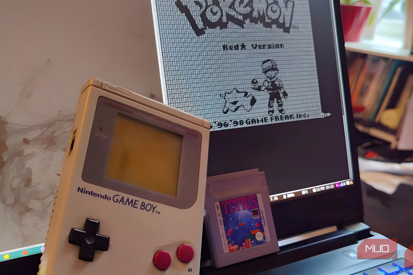 A Game Boy with a Tetris cartridge leaning against a laptop displaying a Pokémon graphic.