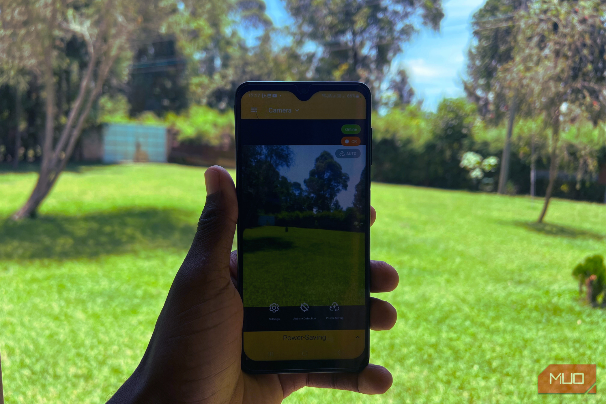 A hand holding a phone showing the AlfredCamera app open streaming a live feed