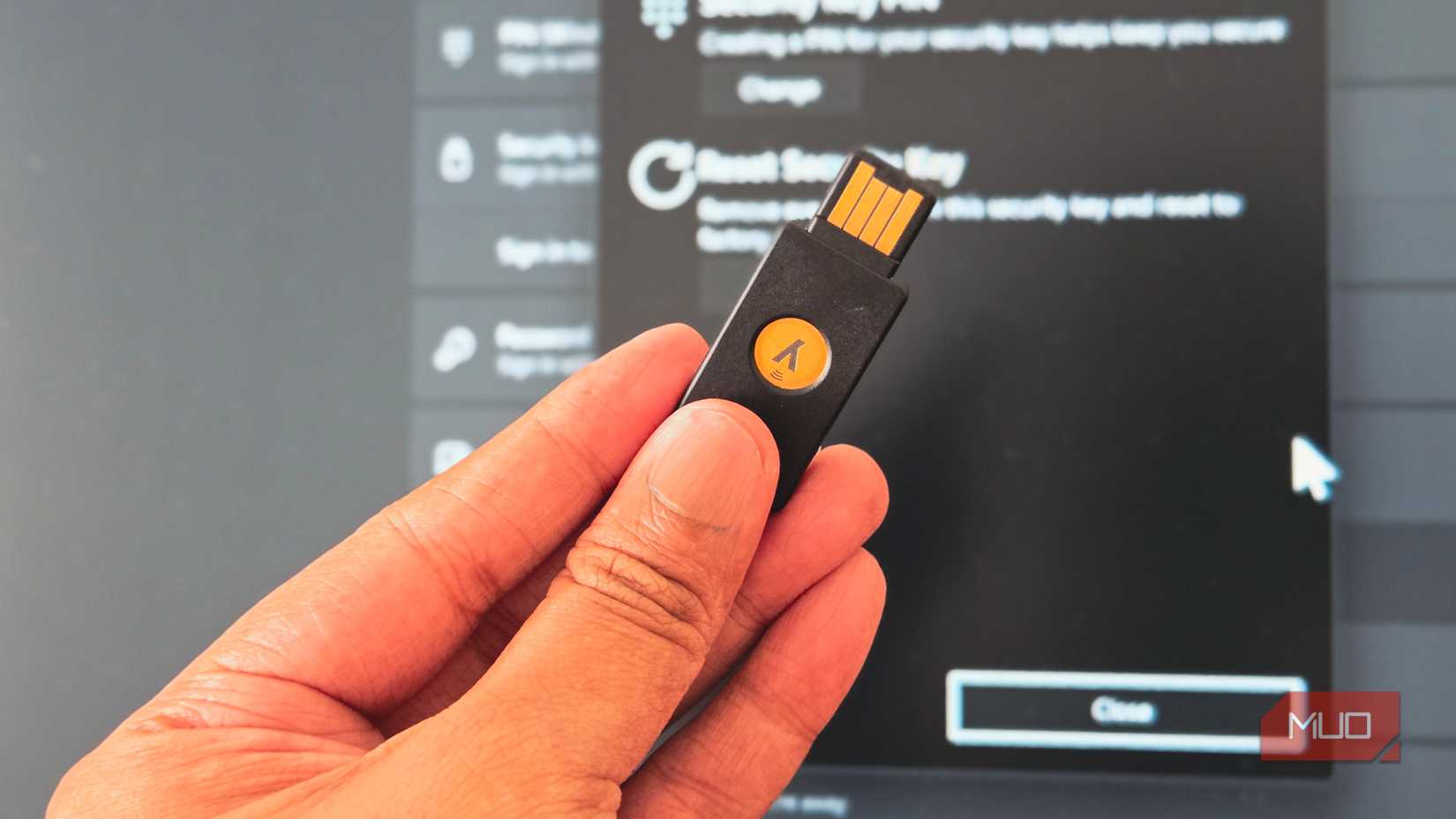 Person holding a YubiKey infront of a Windows 11 desktop monitor