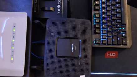 تم وضع جهاز Linksys وجهاز توجيه D-Link على مكتب بجوار لوحة مفاتيح الألعاب