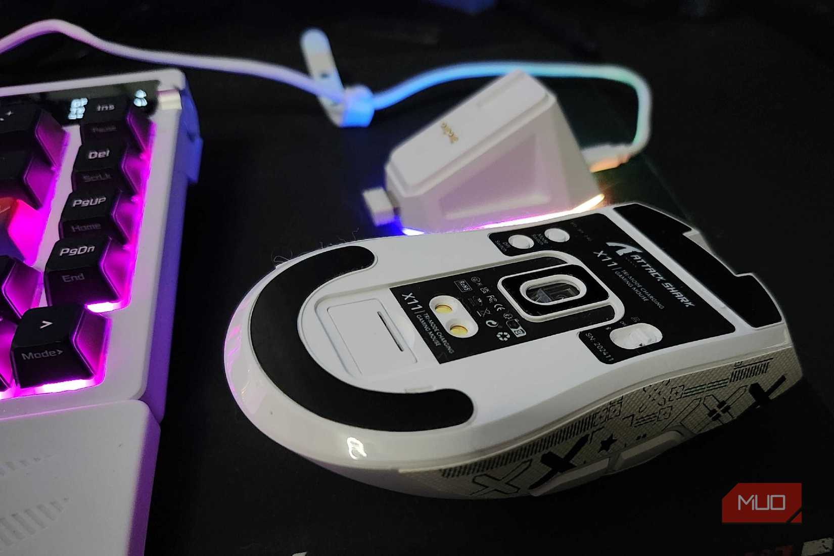 The underside of the Attack Shark X11 mouse, with the charging dock in the background