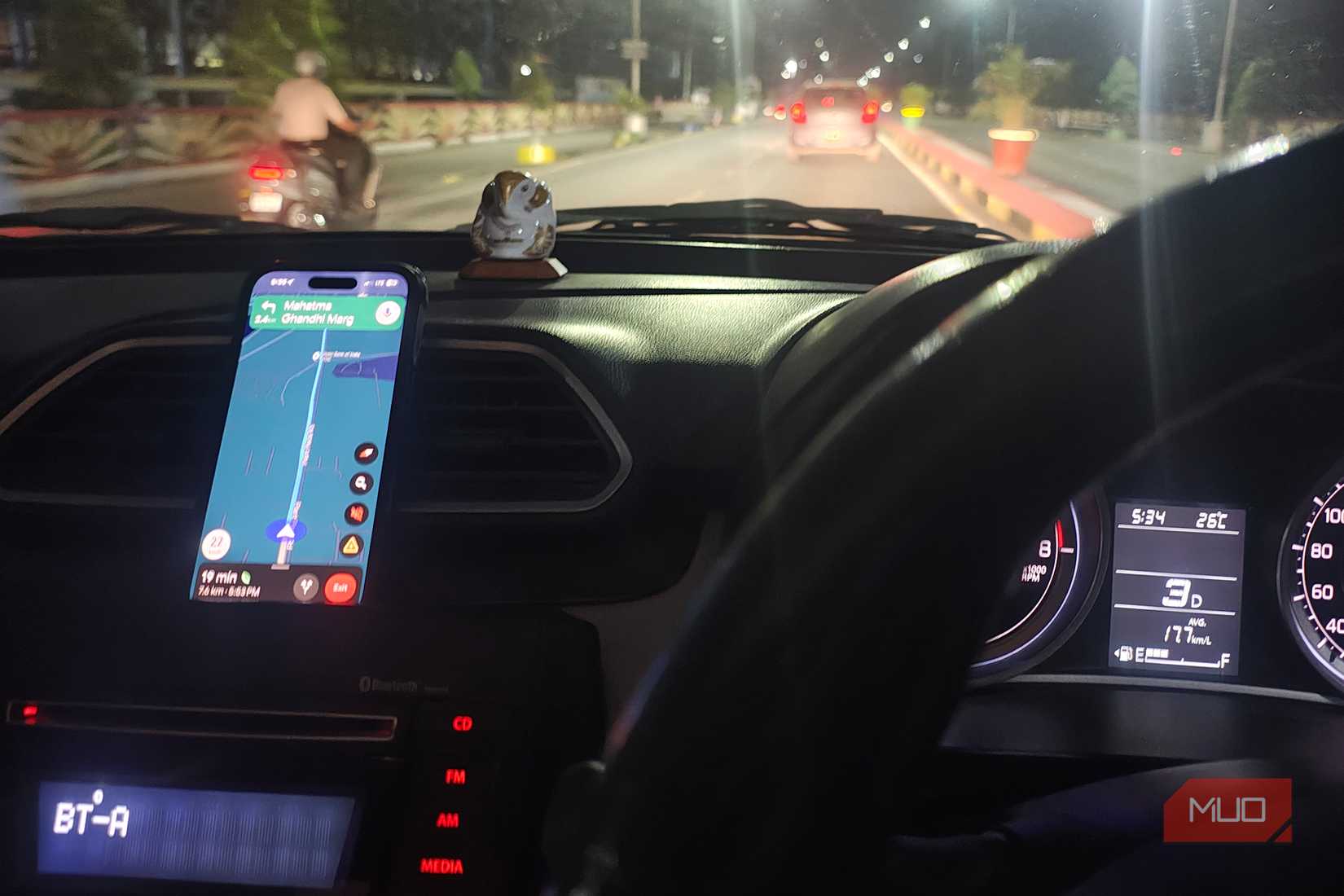 Phone mounted on a car dashboard showing Google Maps navigation during night driving.