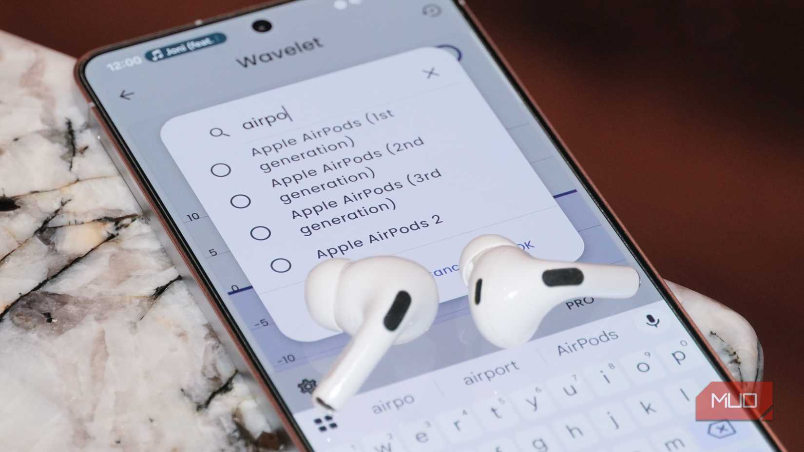 A pair of AirPods Pro 2 atop a phone running the Wavelet app.