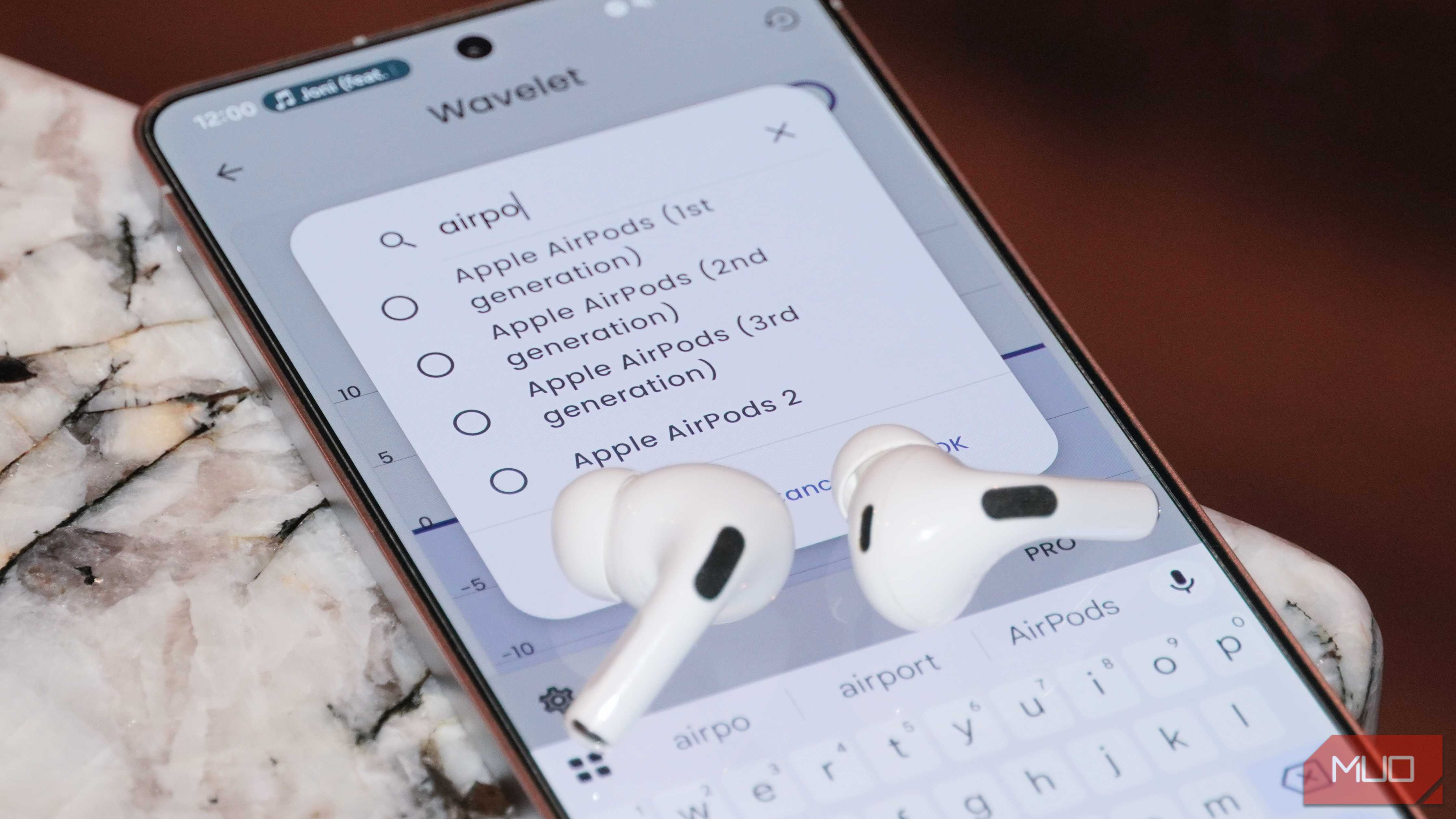 A pair of AirPods Pro 2 atop a phone running the Wavelet app.