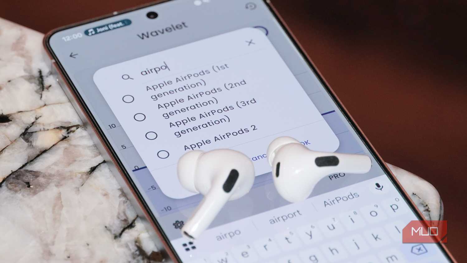 A pair of AirPods Pro 2 atop a phone running the Wavelet app.