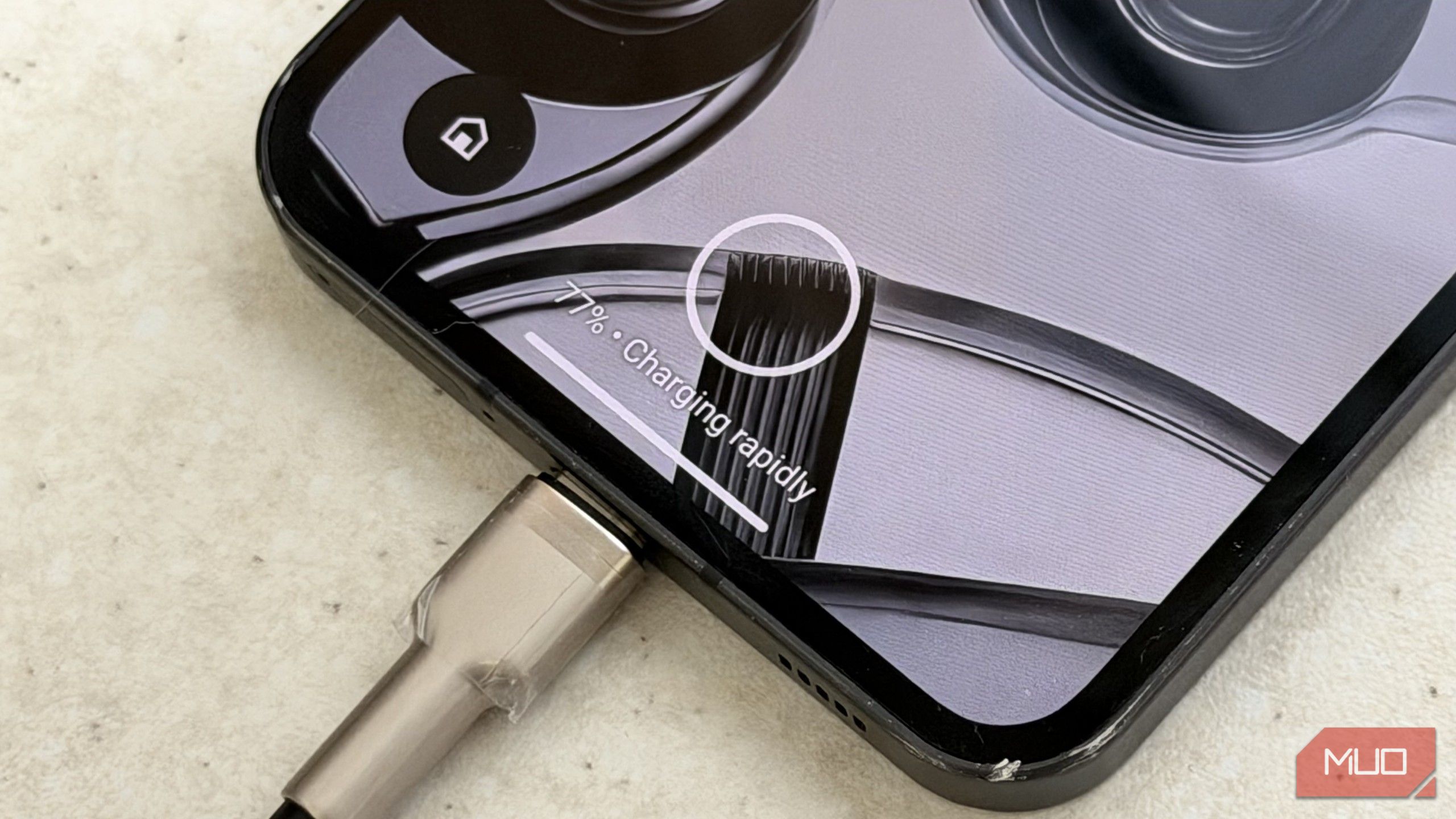 A phone connected to a 100W PD fast charger with the screen saying Charing Rapidly