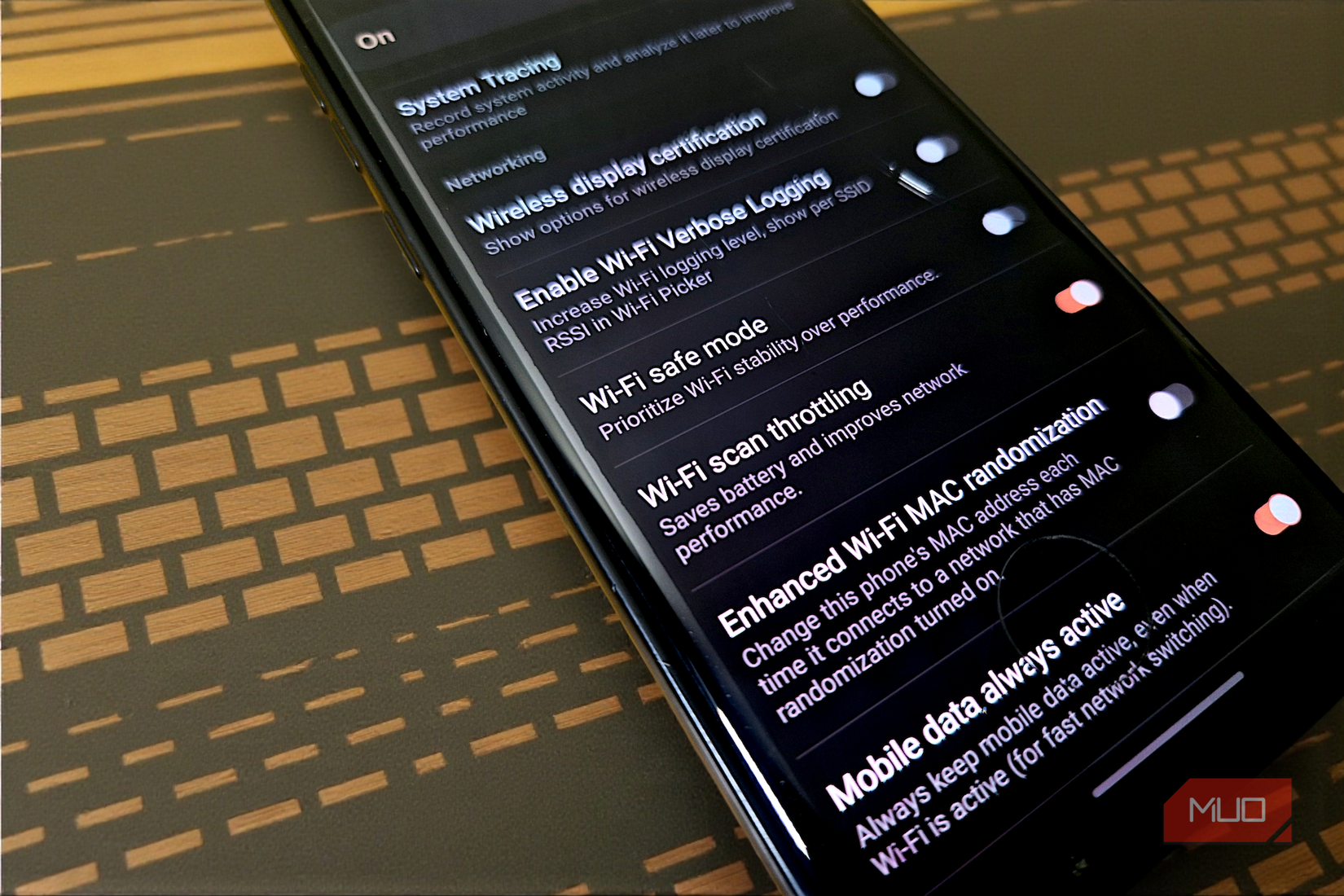 هاتف ذكي ملقى على مكتب يعرض قائمة خيارات Android Developer مع ظهور إعدادات الشبكة.