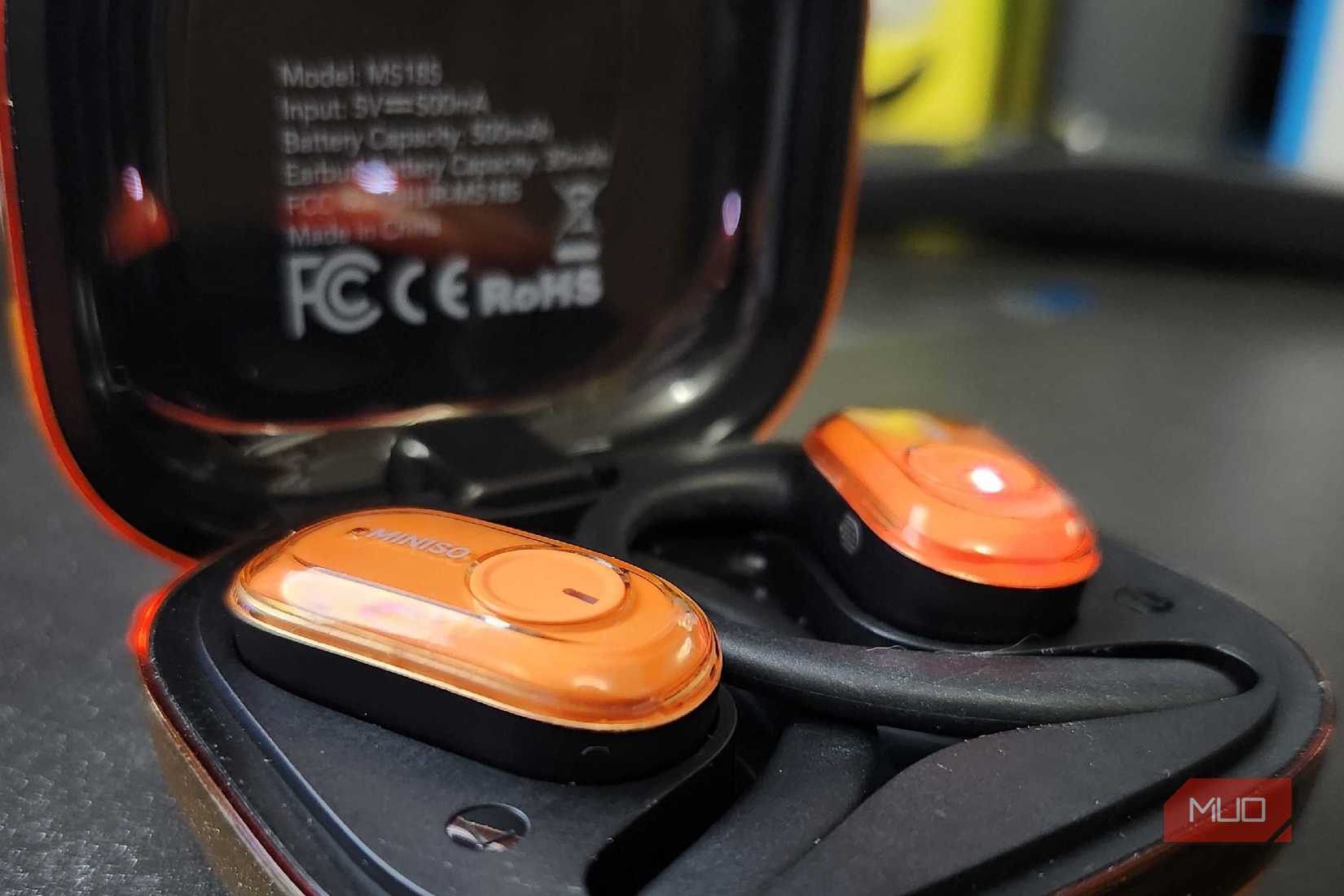 The Miniso MS185 sitting in the charging case, showing the small touch control button