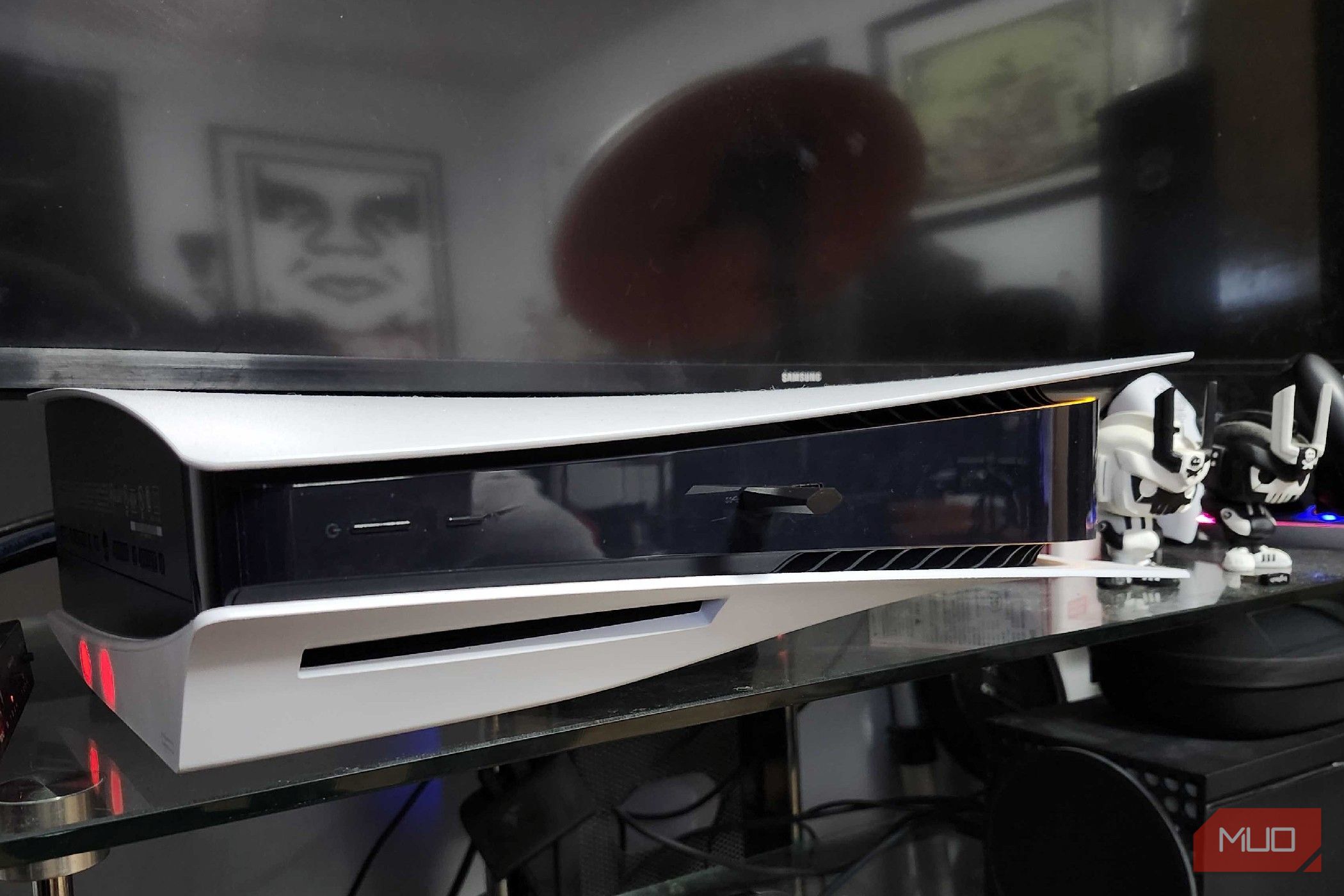 A PlayStation 5 resting below a smart TV on a glass entertainment center