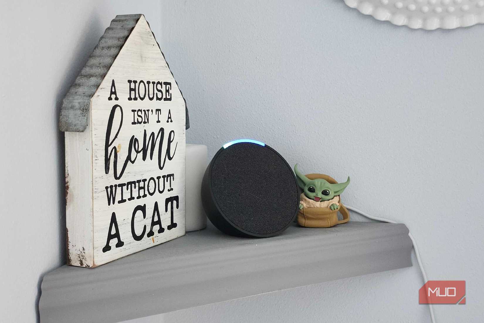 Alexa Echo Dot en una estantería, junto a un cartel y una pequeña figura de Grogu