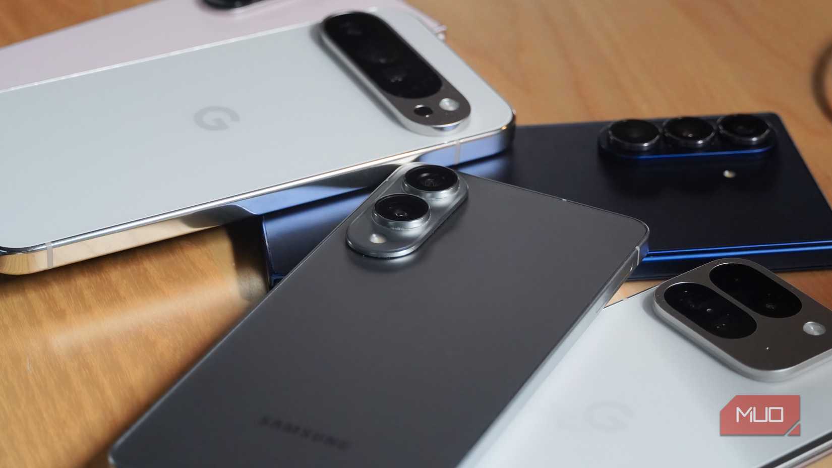 A pile of Android phones on a desk.