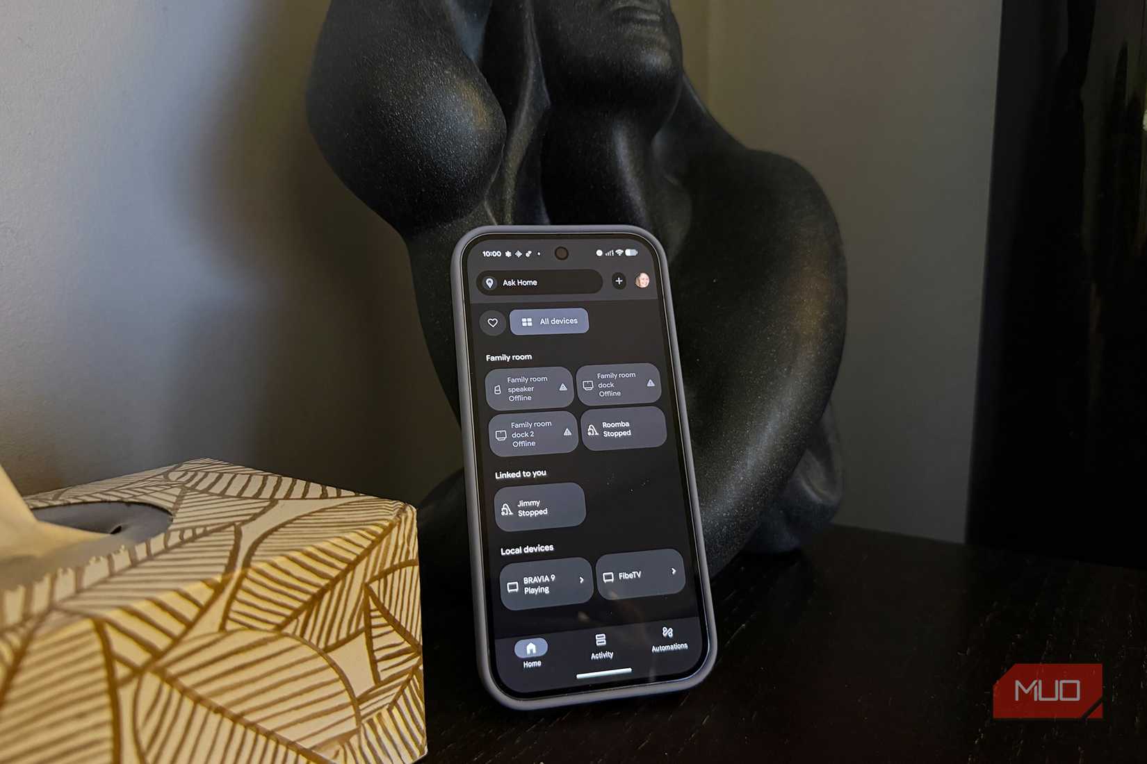 An Android phone propped up on a side table showing a smart home control menu.