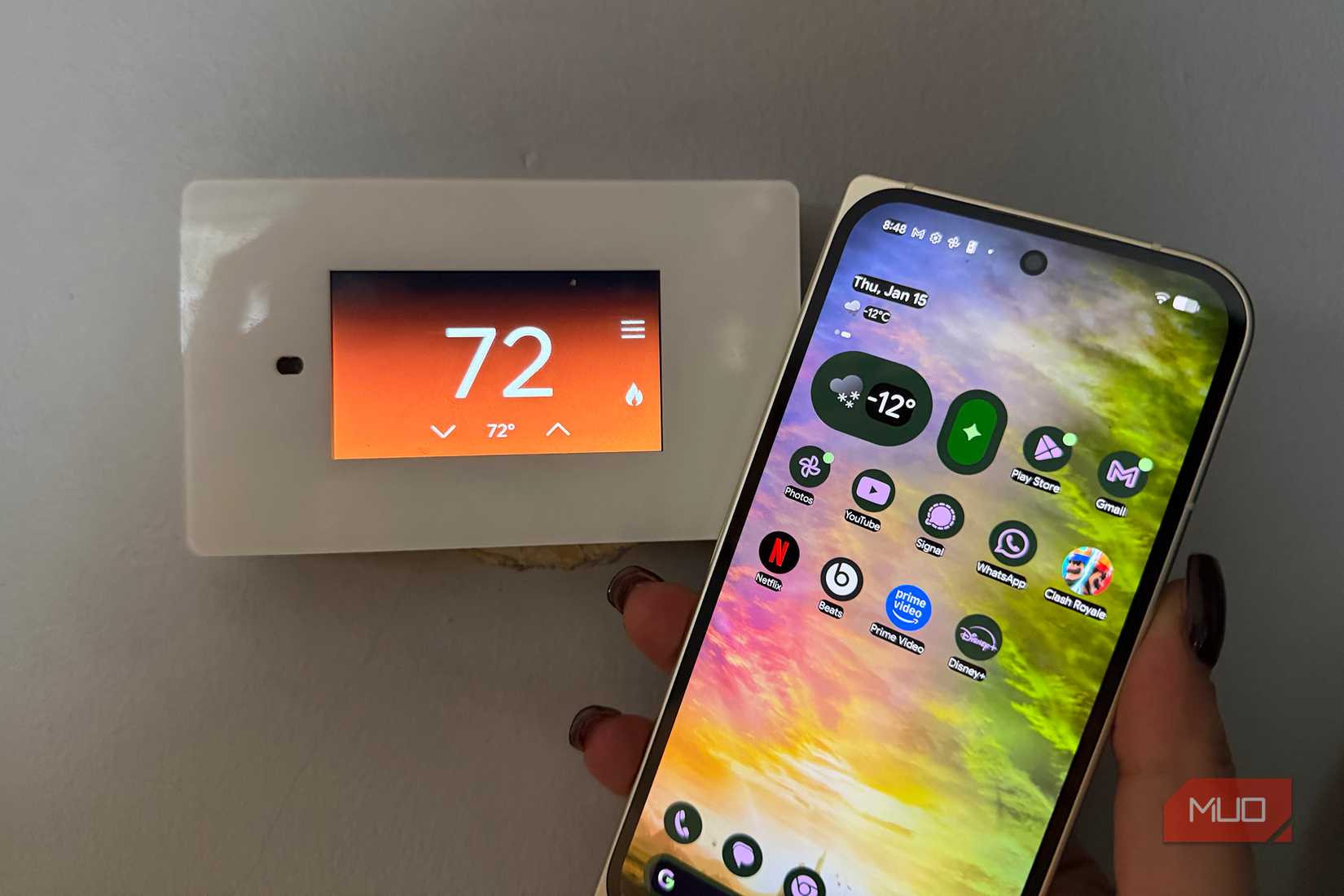 A Google Pixel 10 Pro Fold smartphone held up beside a thermostat showing 72 degrees.