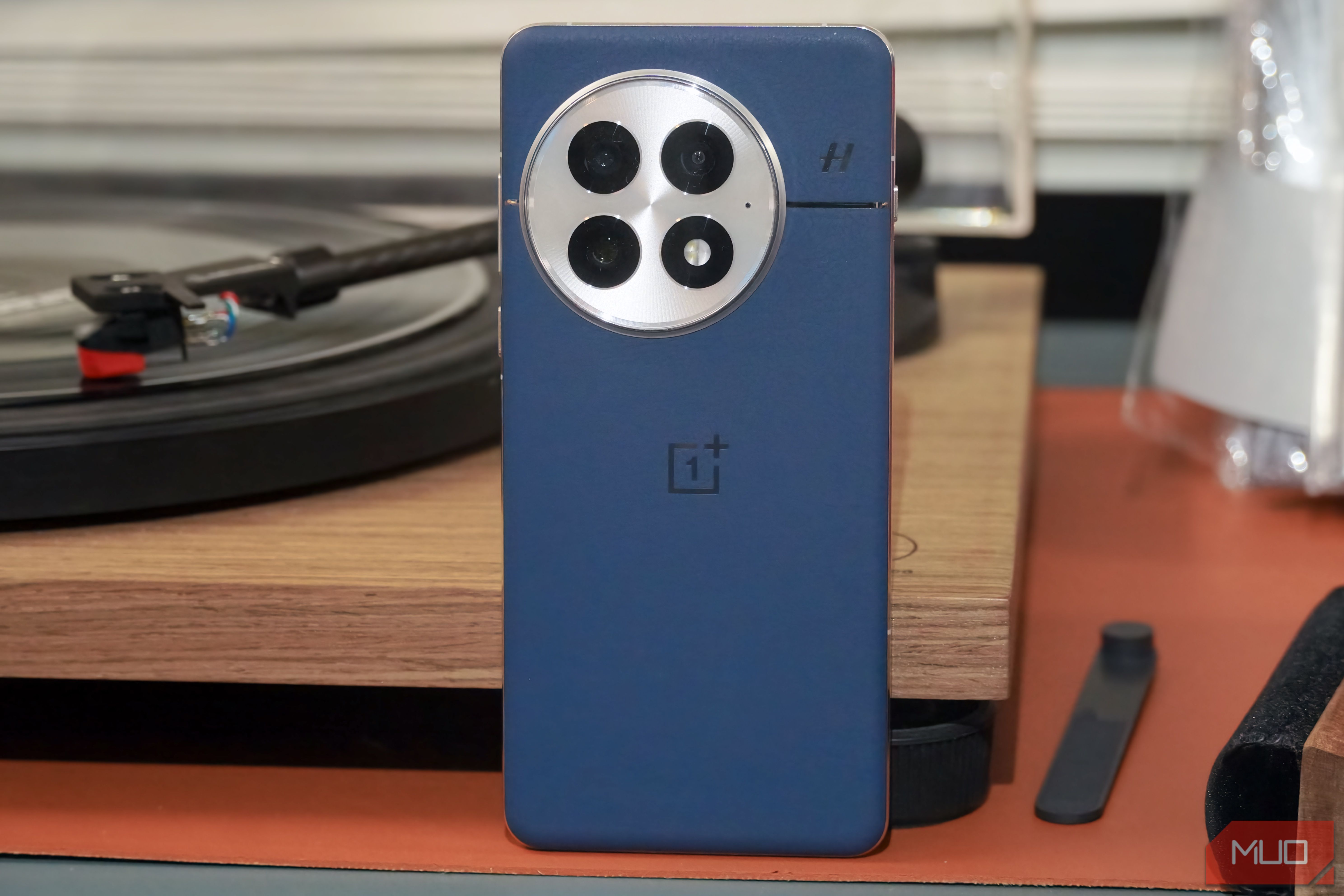 The OnePlus 13 in blue leaning against a vinyl record player.