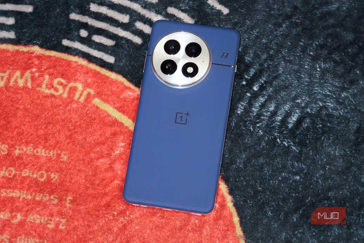 The blue OnePlus 13 on a vinyl-themed rug.