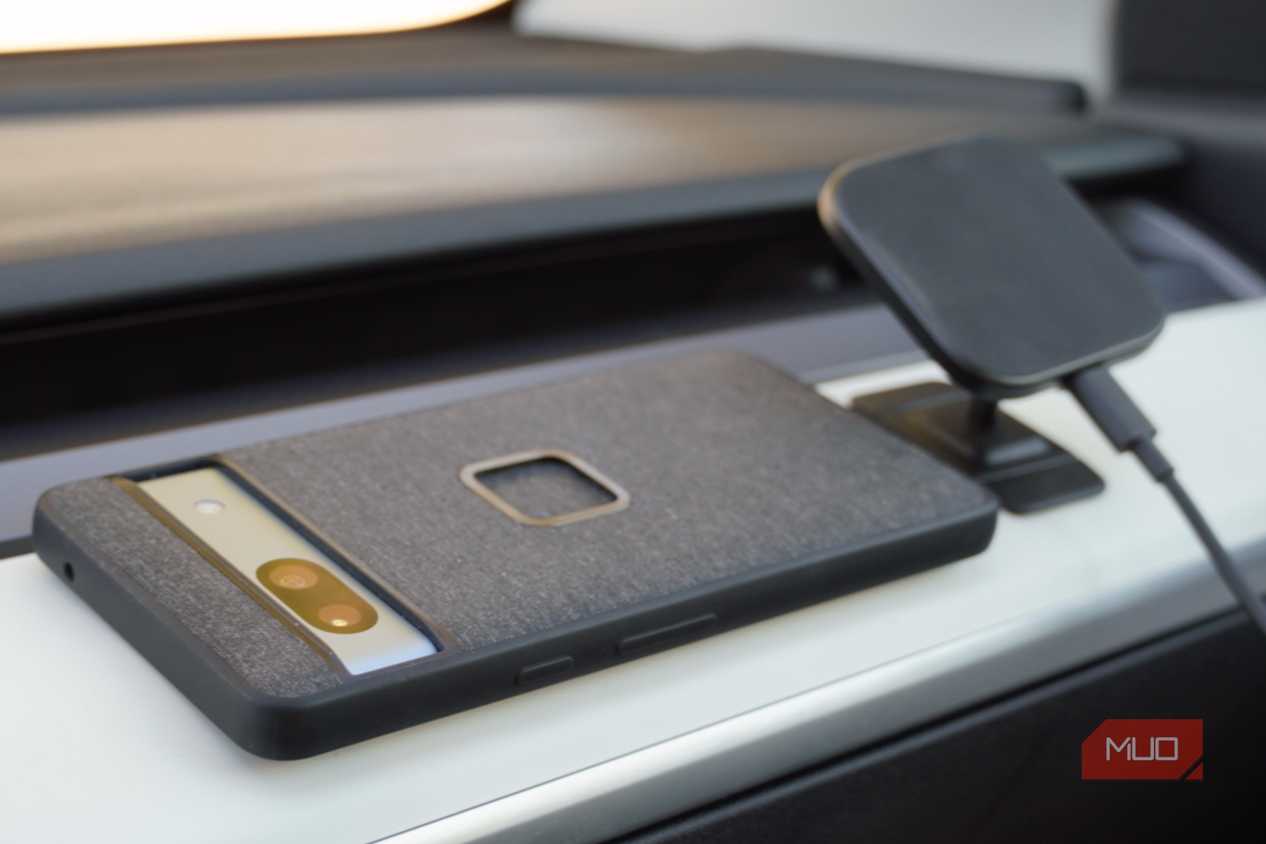The Peak Design Qi2 charging mount next to a Google Pixel 7a on a dashboard.