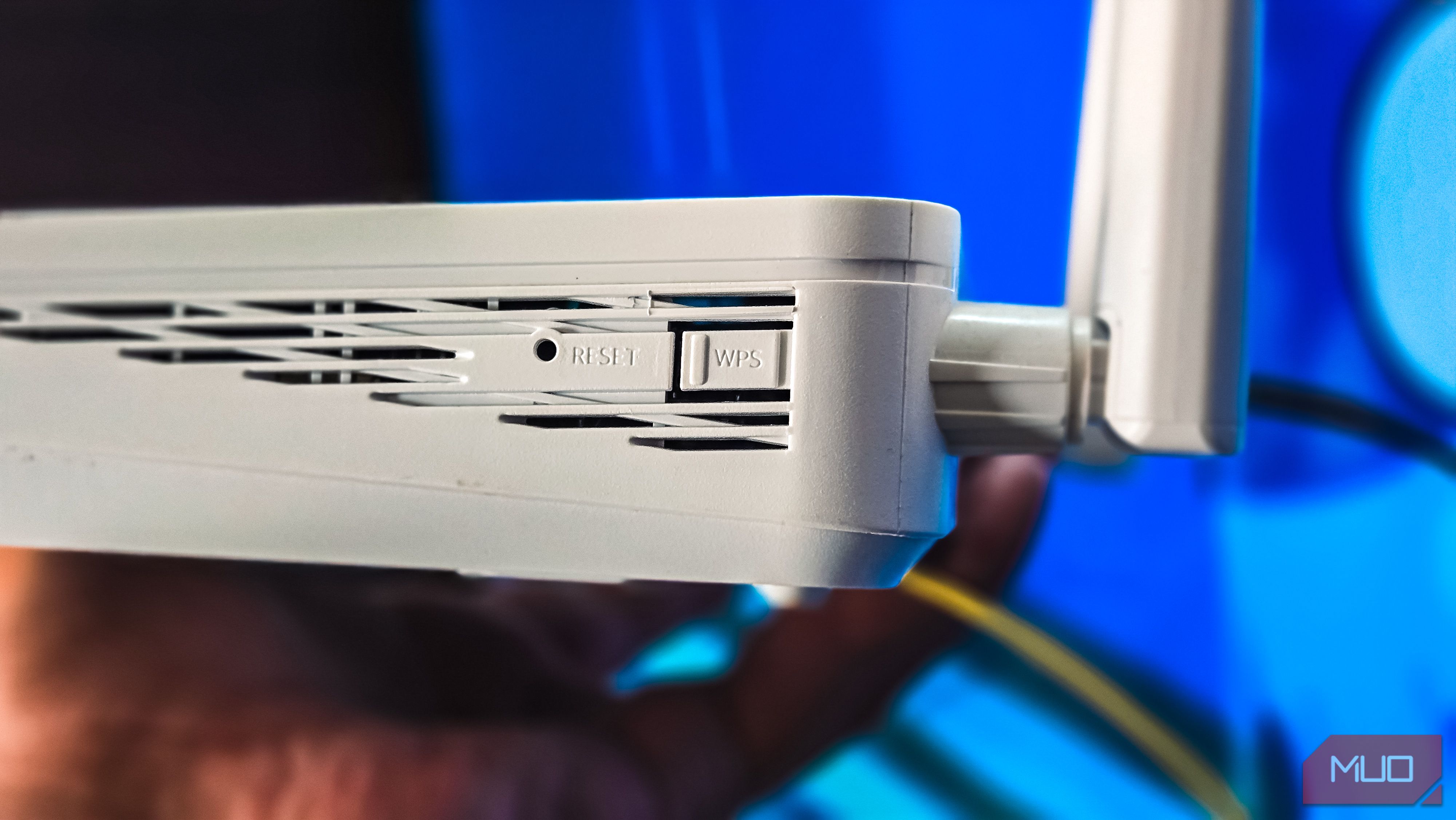 Person holding a router with the Rest and WPS buttons visible