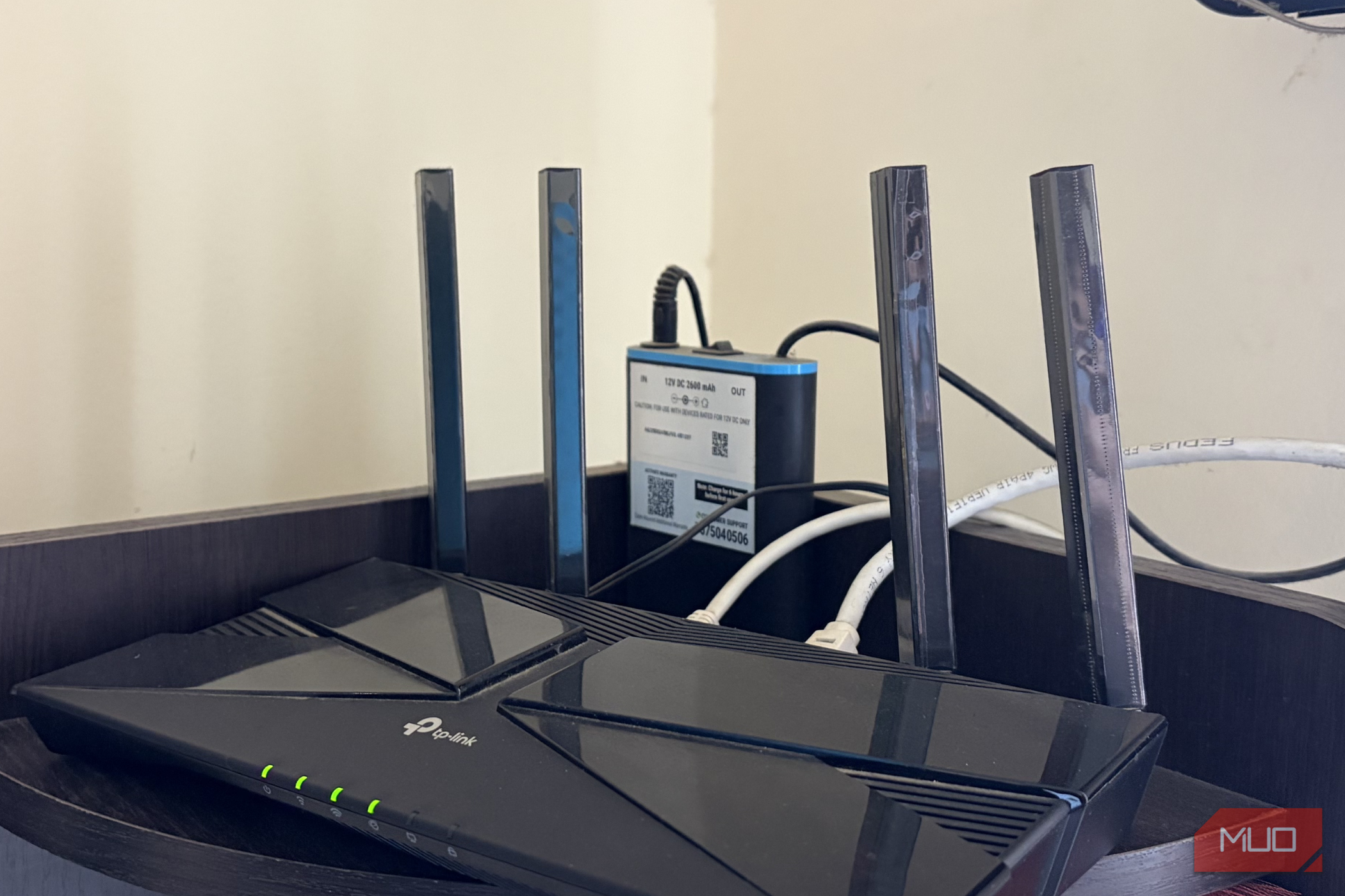 A Wi-Fi router with a mini UPS sitting on a shelf