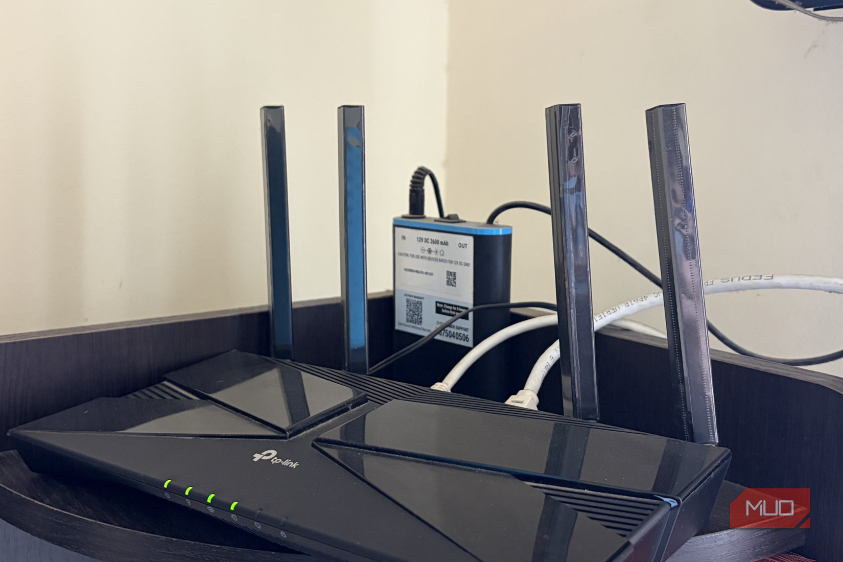 A Wi-Fi router with a mini UPS sitting on a shelf