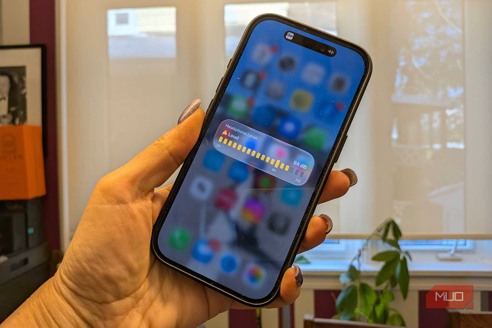 A hand holding an iPhone showing headphone sound level as loud.