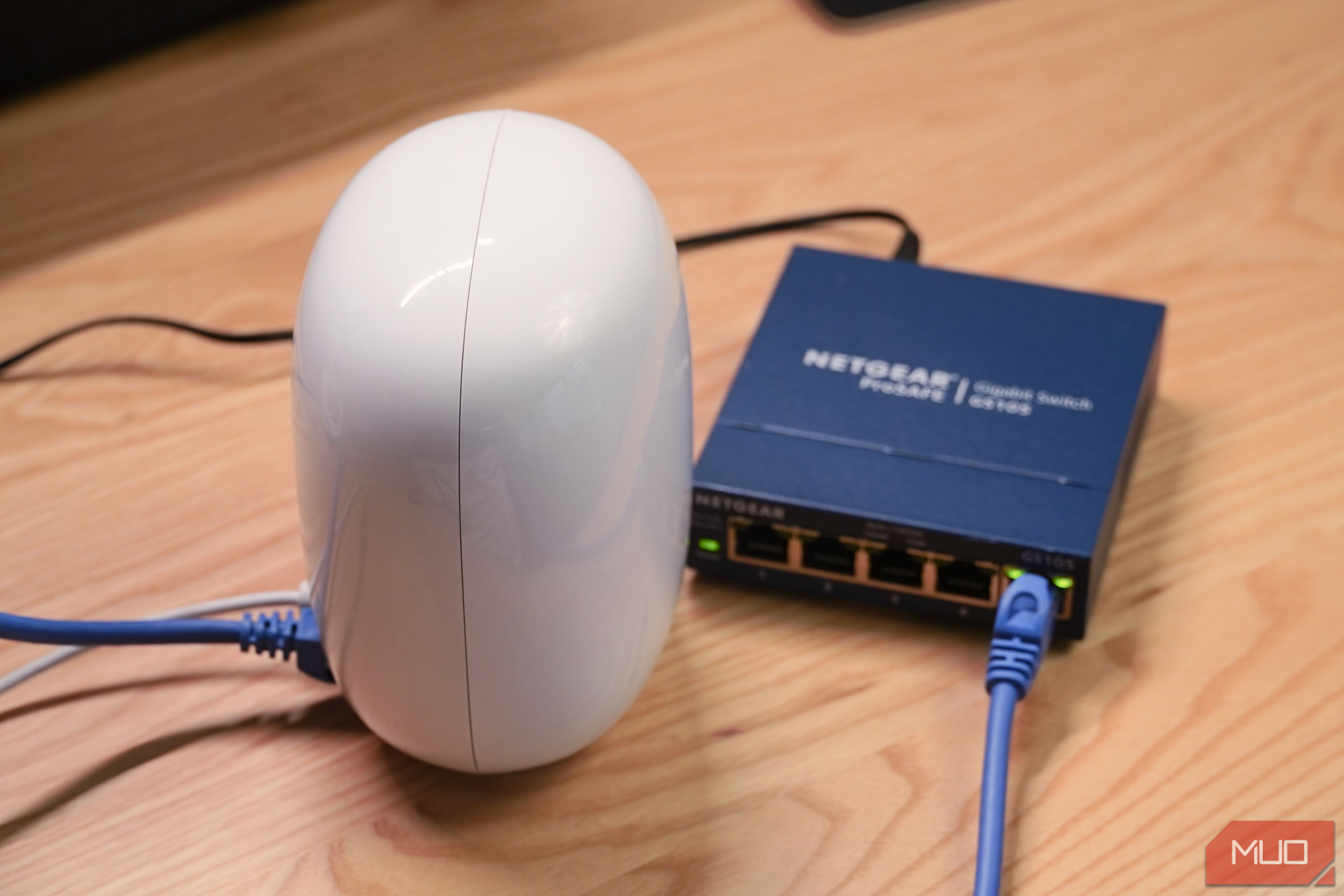 An angled view of a Google Nest Wi-Fi Pro router connected to an unmanaged Ethernet switch.