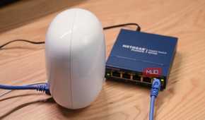 An angled view of a Google Nest Wi-Fi Pro router connected to an unmanaged Ethernet switch.
