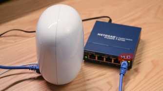 An angled view of a Google Nest Wi-Fi Pro router connected to an unmanaged Ethernet switch.