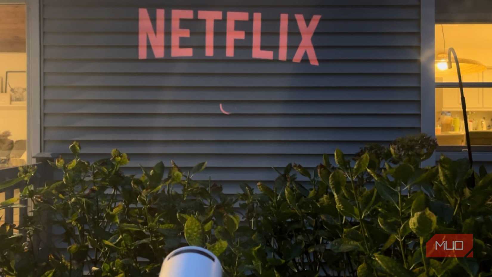 A projector displaying Netflix on the side of a house