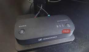 The Sennheiser BTA1 Bluetooth transmitter on a TV stand.
