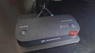 The Sennheiser BTA1 Bluetooth transmitter on a TV stand.