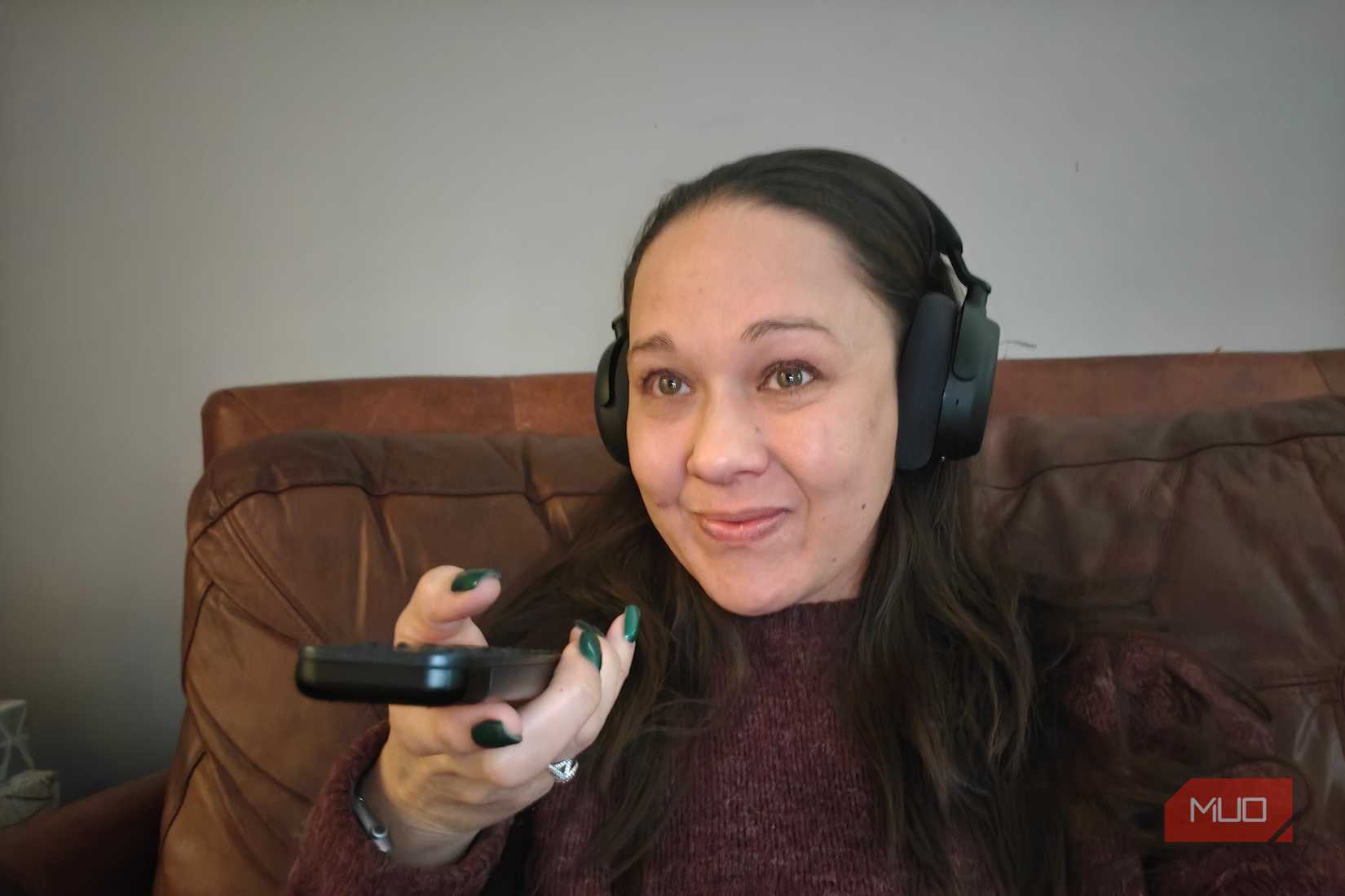 A woman holding a remote and wearing the Sennheiser RS 275 headphones.