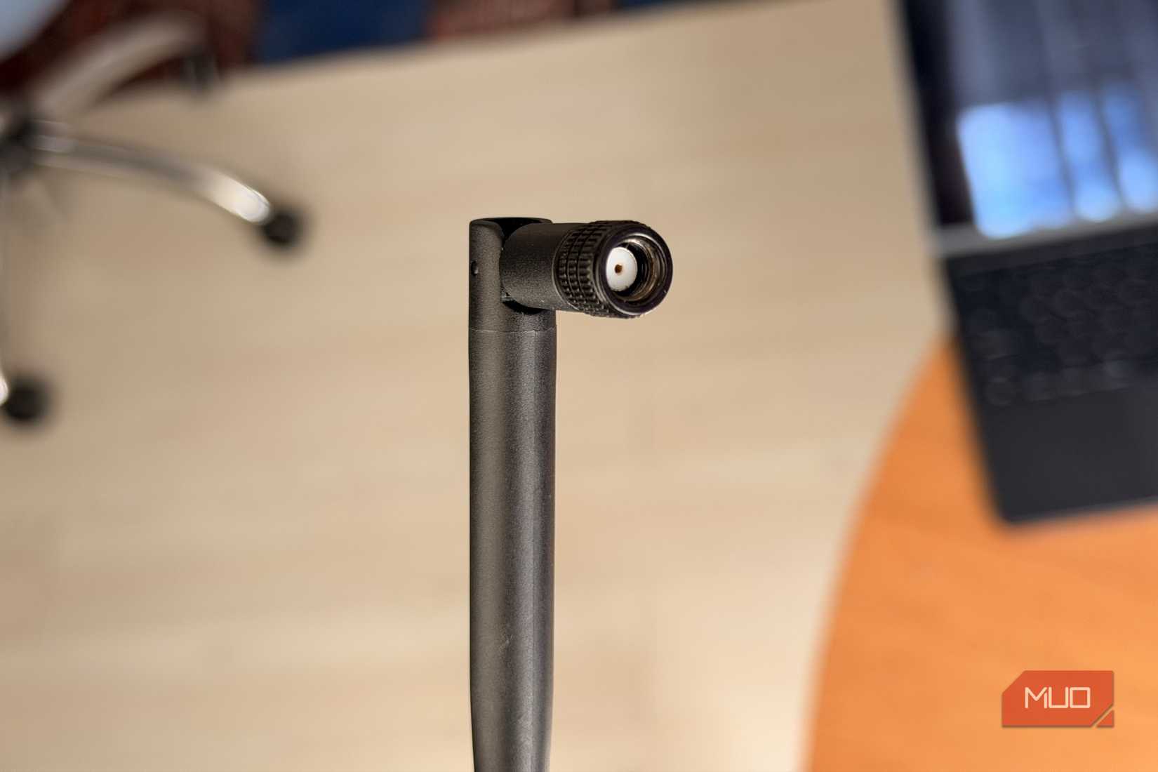 Black WiFi antenna with RP-SMA connector angled on desk