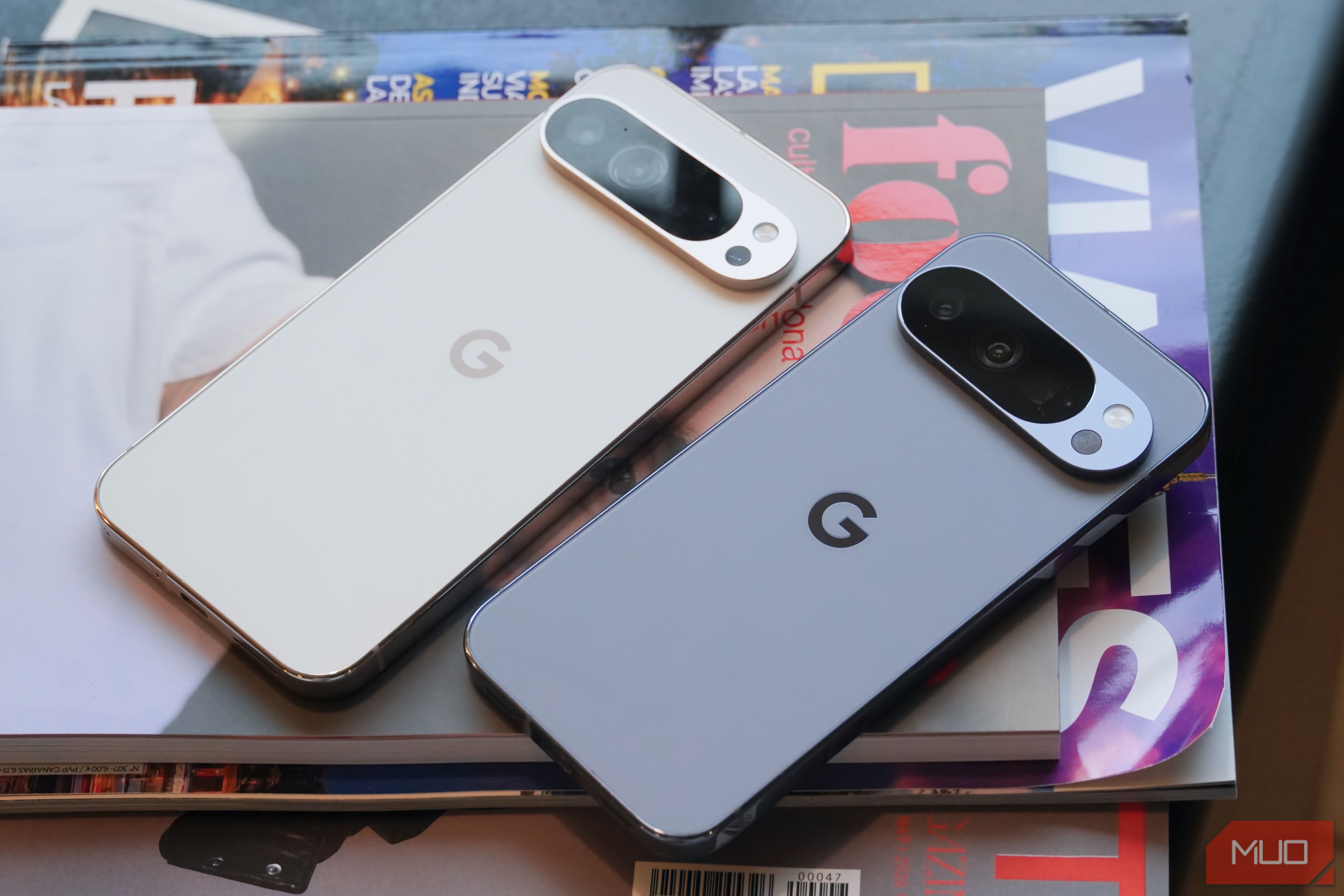 A Google Pixel 9 Pro XL beside a Pixel 10 Pro on a stack of magazines.