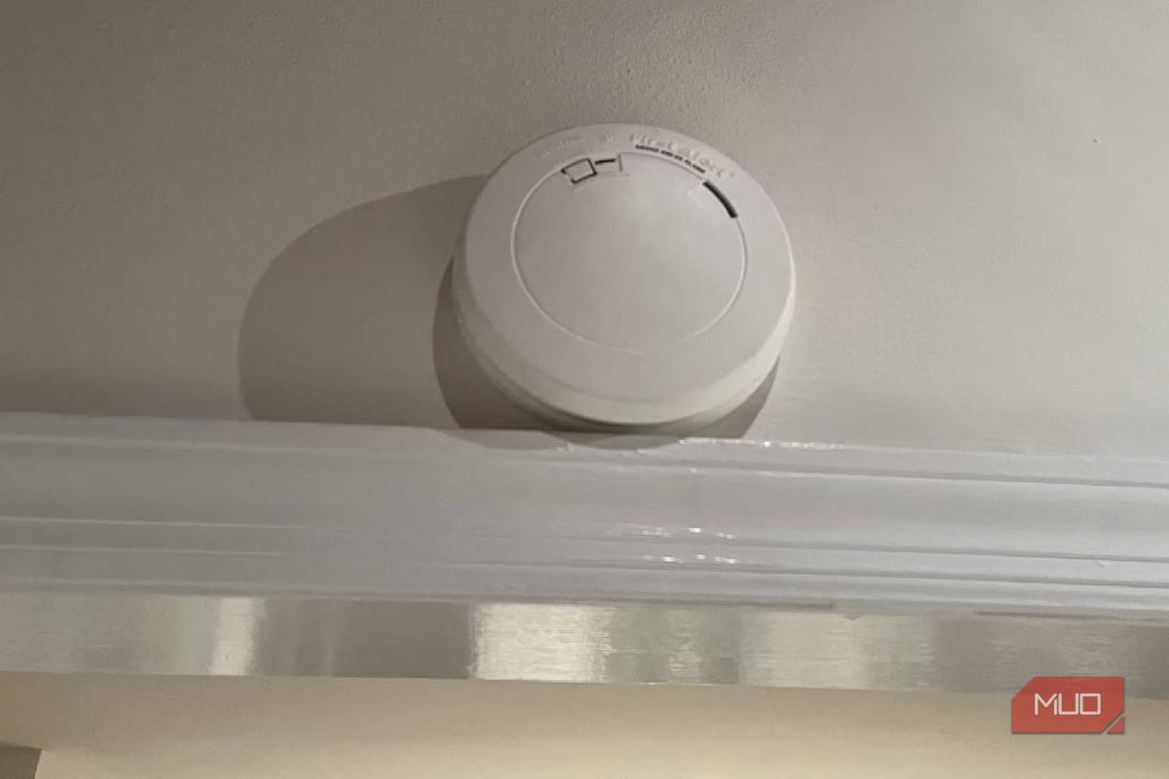 A smoke alarm sits on top of a door