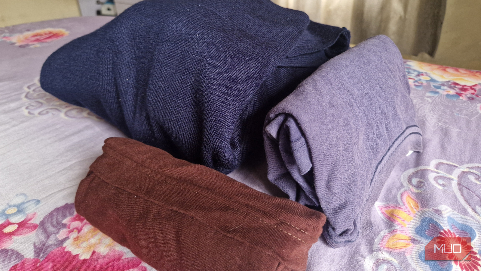 Three sets of fabric, one rolled, one folded with the konMari style, and the last a bundle of clothes wrapped together.