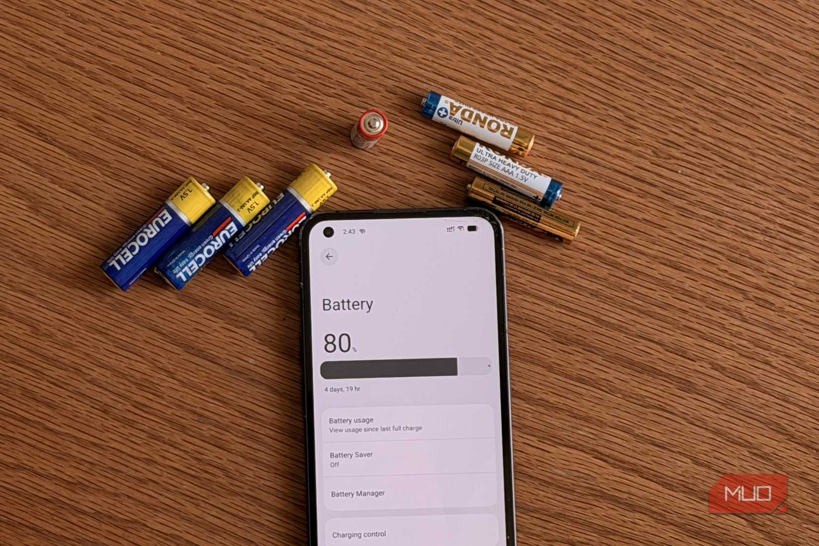 AA and AAA batteries next to Android smartphone showing battery settings