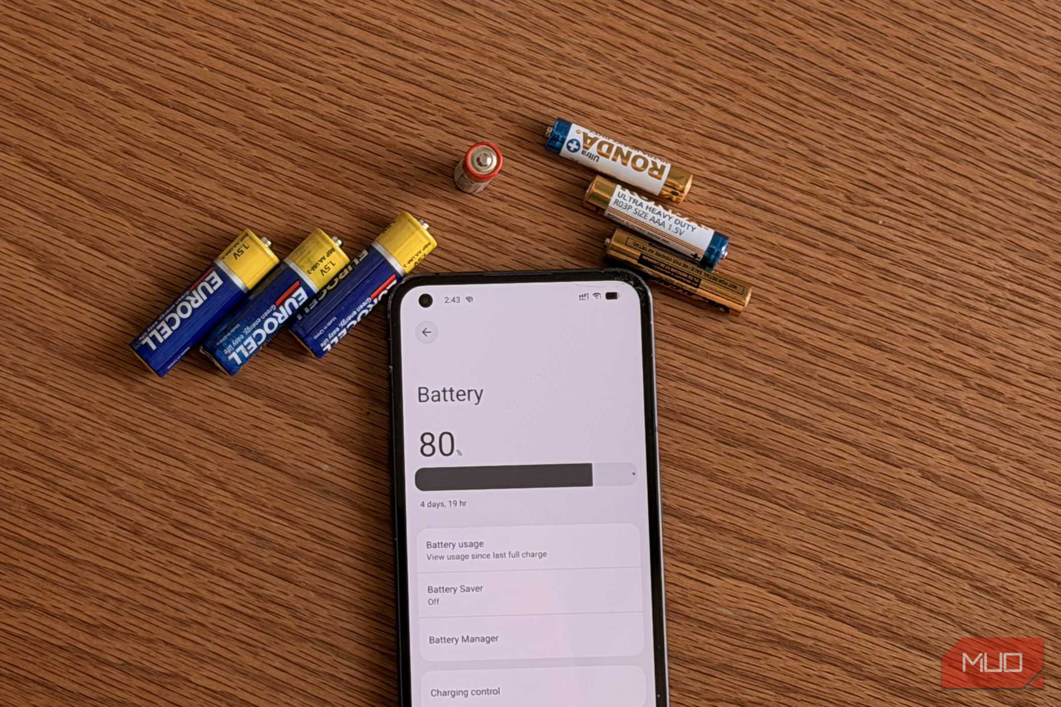 AA and AAA batteries next to an Android phone showing the battery settings