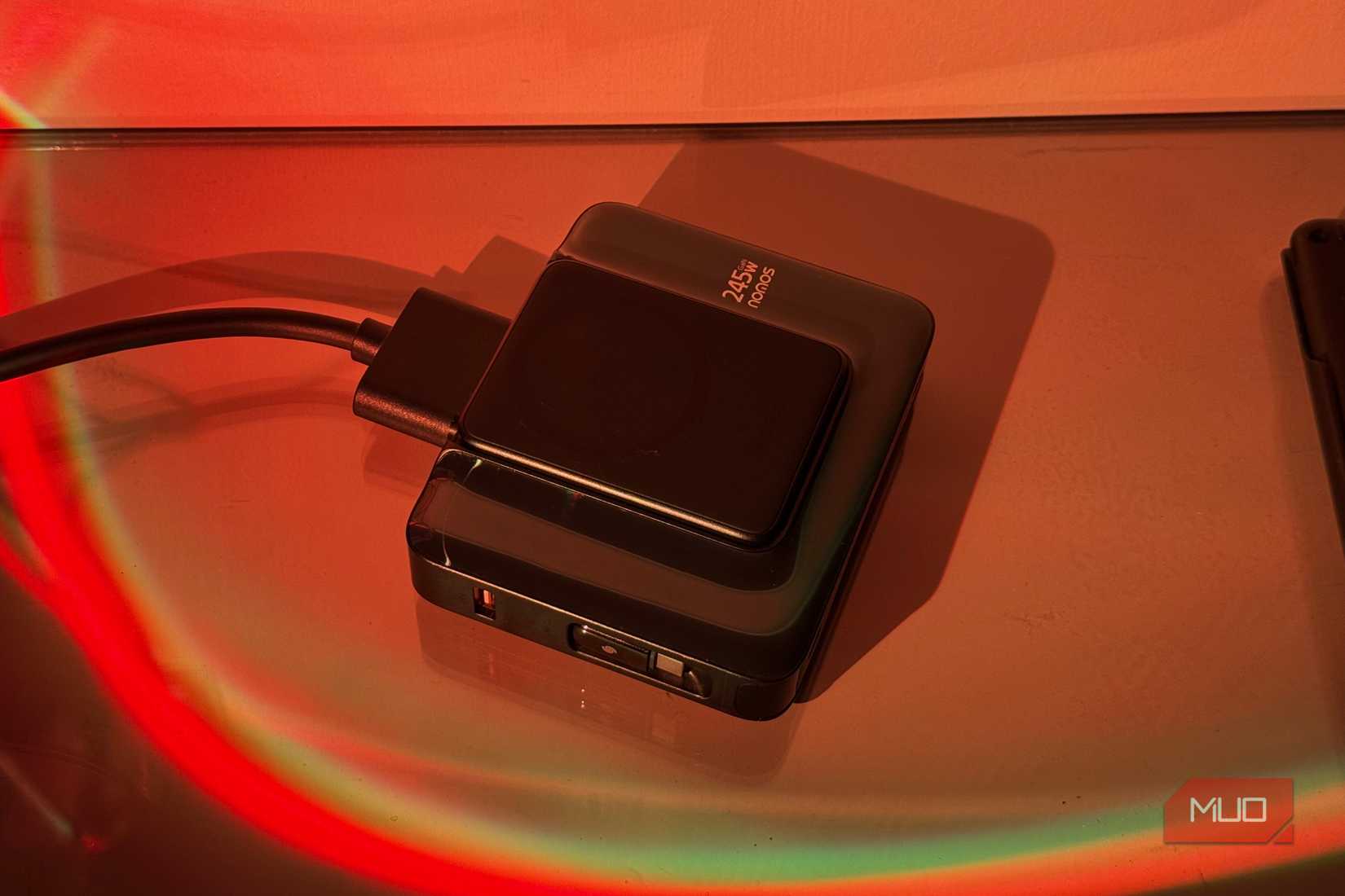 black portable hard drive with cable on surface illuminated by red and green neon lighting