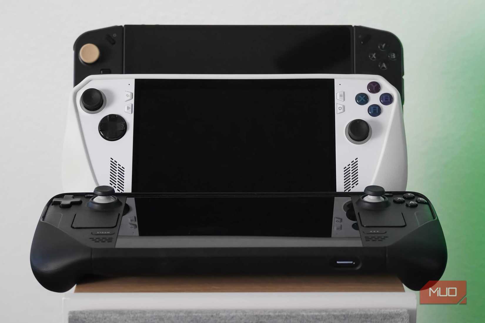 PC gaming handhelds resting on a speaker.