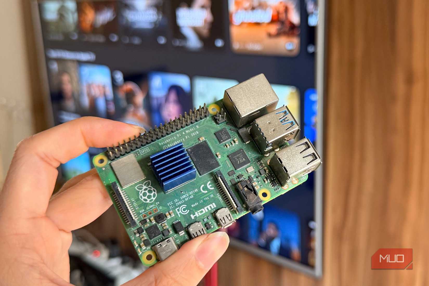 Hand holding a Raspberry Pi 4 in front of a smart TV